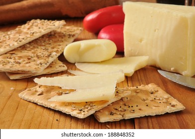 A Wedge Of Asiago Cheese On Flatbread Crackers And Gouda Cheese In Red Wax Wrappers