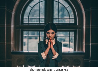 Wednesday Addams. Angry Girl Student After The Exam With Bloody Hands. Gothic Look For A Halloween Party.Creative Colors.The Background Of The Old Castle Window