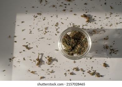 Weed Store. Glass Jar With Dried Cannabis Buds On White Background With Crushed Marijuana.