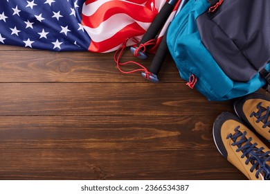 Weekend adventure exploring the great outdoors. Top view flat lay of american flag, hiking shoes, rucksack, trekking sticks on wooden background with promo area - Shutterstock ID 2366534387