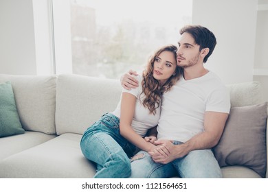 Weekend holiday daydream serenity concept. Portrait of attractive calm couple sitting on sofa in living room hugging looking away enjoying time together