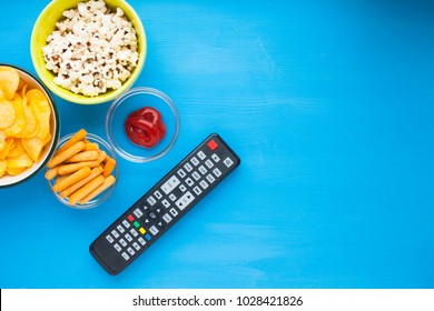 Weekend at home, leisure lifestyle concept. Set of snacks in glass bowls (chips, popcorn, ketchup), remote controllers (consoles) and joysticks for games on the blue background. Top view. Close up. - Powered by Shutterstock