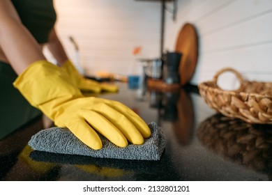 Weekend homework. A woman is cleaning the kitchen at home. Close-up of hands in yellow gloves cleaning the countertop, working kitchen surface