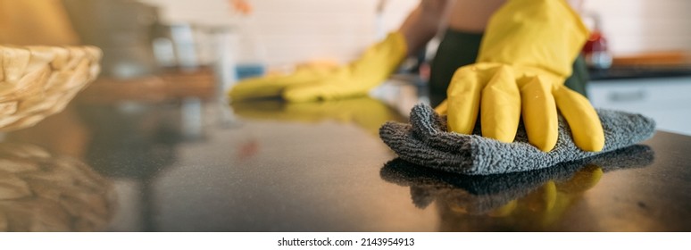 Weekend homework. A woman is cleaning the kitchen at home. Close-up of hands in yellow gloves cleaning the countertop, working kitchen surface