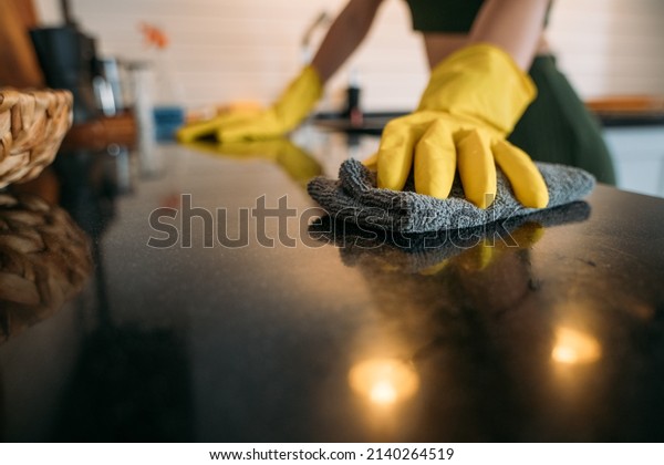 Weekend homework. A woman is cleaning the kitchen\
at home. Close-up of hands in yellow gloves cleaning the\
countertop, working kitchen\
surface