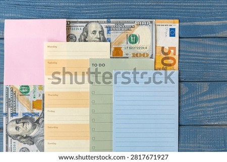 Weekly planner and blank notes arranged with dollar and euro banknotes