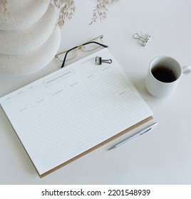 Weekly Planner Mockup With Copy Space On Home Desk Workspace With Modern Vase, Pen, Cup Coffee Top View On White Table.  Minimalist Lifestyle Neutral Colors.