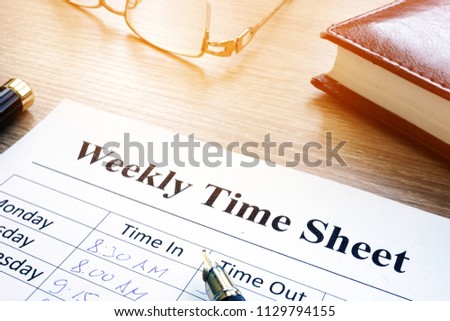 Weekly time sheet and pen on an office desk.