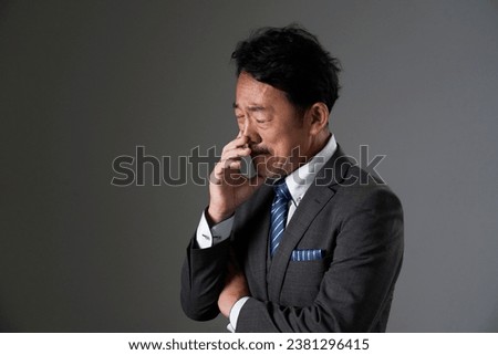 Weeping Asian middle aged businessman in black background
