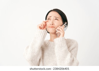 Weeping Asian middle aged woman with the smartphone in white background