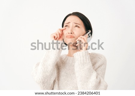 Weeping Asian middle aged woman with the smartphone in white background