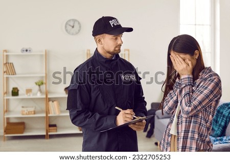 Weeping woman talking to police officer after breaking into house. Policeman in uniform writing down testimonies and trying to calm young woman. Police investigation concept