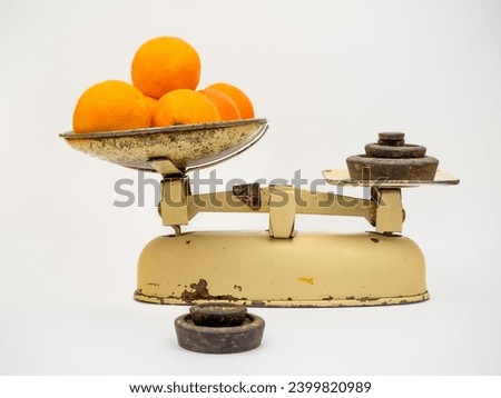 weighing out oranges on a traditional analogue fulcrum weighing scles with individual metal weights