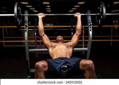 Weight lifter at the bench press lifting a barbell on an incline bench