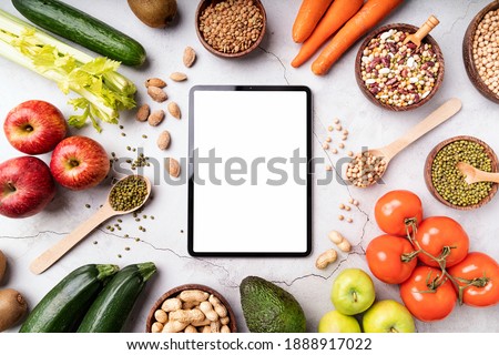 Weight lose and dieting concept. Top view of a tablet with white screen for mock up with healthy foods. Copy space. Mock up design