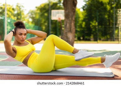 Weight Loss Concept. Confident Sportive Young Black Woman Doing Side Bicycle Crunches Bringing Elbow Toward Knee With Raised Leg On Yoga Mat, Training Outside At Court. Pilates And Warm Up Concept - Shutterstock ID 2142868461