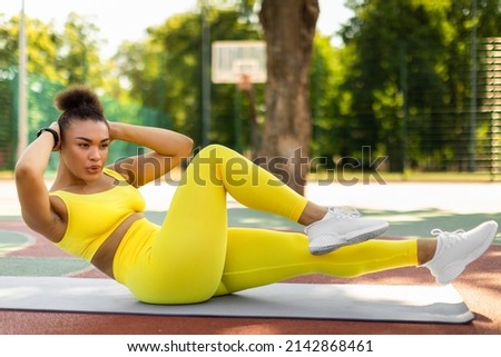 Weight Loss Concept. Confident Sportive Young Black Woman Doing Side Bicycle Crunches Bringing Elbow Toward Knee With Raised Leg On Yoga Mat, Training Outside At Court. Pilates And Warm Up Concept