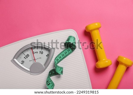 Weight loss concept. Scales, dumbbells and measuring tape on pink background, flat lay