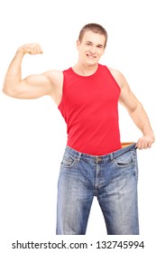 Weight Loss Man Showing His Muscles And Holding An Old Pair Of Jeans Isolated On White Background