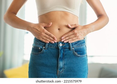 Weight Loss. Unrecognizable Slim Lady Touching Flat Stomach Framing Belly Button With Hands Posing Standing At Home. Slimming And Abdomen Health Concept. Cropped Shot