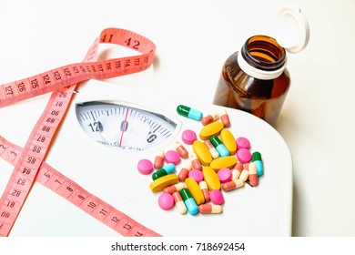 Weight Scale,Weight Loss Pills And Supplements  With Pink Measuring Tape Concept Of Health Care. Selective Focus