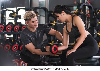 Weight training instructor train the beginner apprentice for muscle building. Fitness personal trainer advise a woman for physical workout.