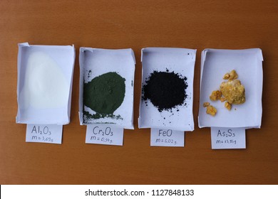 Weighted Amounts Of Different Minerals: White Alumina, Green Chromium Oxide, Black Iron Oxide, Yellow Arsenic Sulfide, With Mass Values.