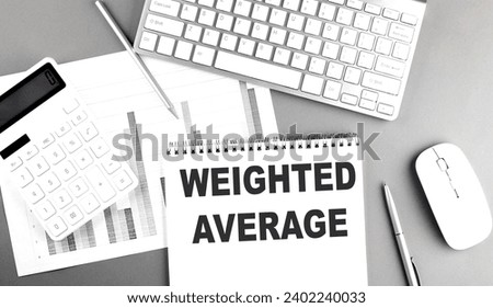 WEIGHTED AVERAGE text on notebook with keyboard on grey background