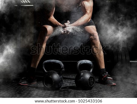 Weightlifter clapping hands and preparing for workout at a gym. Focus on dust