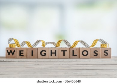 Weightloss Sign With Measure Tape On A Wooden Table