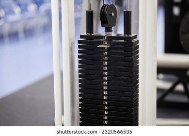 Weights on the simulator in the gym. Heavy plates of black iron, stacked from a power machine in a fitness room. Load the iron pancakes with a gym machine. Sport equipment. Sports simulator.
