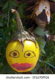 Weird Garden Decoration With An Apple With Painted Face And A Planter With A Rusty Tin Scarecrow