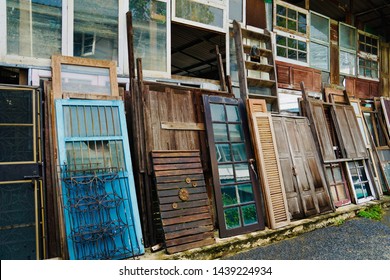 Weird walls from house parts. Scrap of old doors and Damaged house windows on the wall. Second-hand goods stores, old doors or partially damaged windows. Used vintage shops on the roadside.