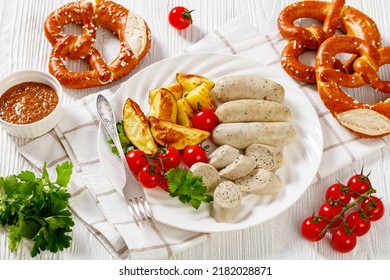 Weisswurst, Bavarian White Sausage Of Minced Veal, Pork Back Bacon, Spices And Parsley On White Plate With Roast Potato, Fresh Tomatoes, Soft Pretzels, Sweet Mustard, Horizontal View From Above