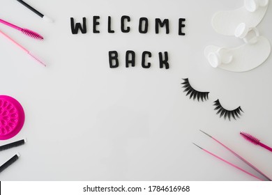 Welcome Back In Black Letters Against A White Background Framed By Beauty Business Eyelash Treatment Products, Tools And Accessories.  Lash Artist Beauty Salon Concept Background Welcoming Clients