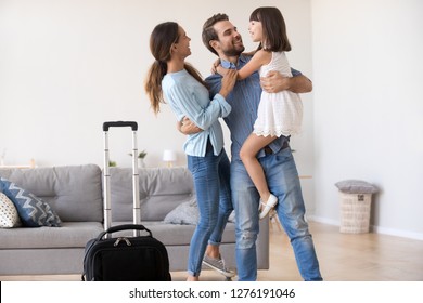 Welcome back dad concept, happy father businessman embracing kid child daughter and young wife returning from business trip, loving daddy arriving coming home excited by family reunion concept - Powered by Shutterstock