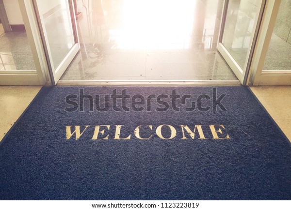 Welcome blue mat in front\
of door, shop