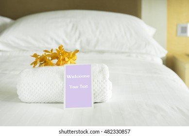 Welcome Card Placed Inside A Hotel Room Bed With Yellow Orchid.