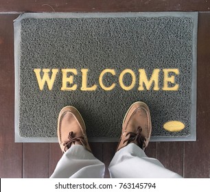 Welcome carpet gray color with shoe on it.