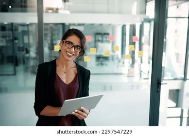 Bienvenidos a la era digital. Retrato recortado de una atractiva joven empresaria parada sola en su oficina y trabajando en una tableta.