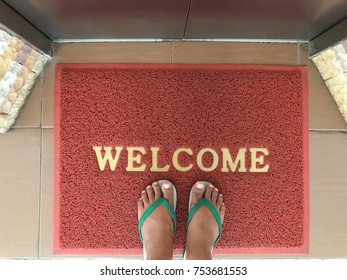 Welcome Door Mat With Male Feet In Front Of Elevator.