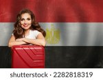 Welcome to Egypt. Cheerful woman with red suitcase on Egyptian flag background. Travel, work, education and internship in Egypt