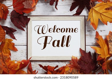 Welcome Fall text message top view with maple leaf decoration on wooden background