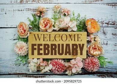 Welcome February Text On Wooden Board With Flowers Frame On Wooden Background