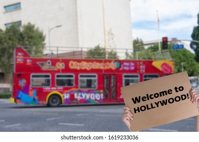 Welcome To Hollywood Concept With Red Sight Seeing Bus In Blurred Background