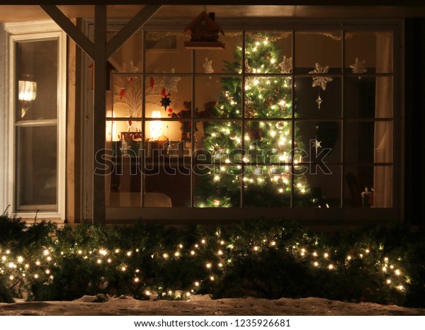 クリスマスツリーおかえり 家の中に輝くクリスマスツリーを飾り付けた窓と 明るい屋外装飾 夜景 明るいぼかし クリスマスと新年の休暇の背景 の写真素材 今すぐ編集
