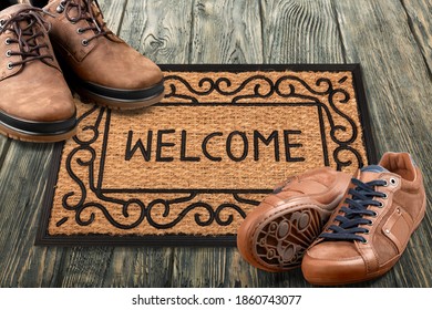 Welcome Home Entrance Door Mat At Condo Floor With Couples Pairs Of Shoes Moving In Together.