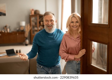 Welcome Home. Joyful Mature Couple Opening Door Of New House, Smiling To Camera Meeting And Greeting You Indoors. Husband And Wife Standing In Doors Of Their Apartment. Own Real Estate - Powered by Shutterstock