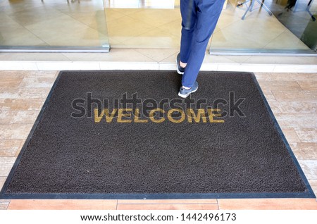 A welcome mat at the entrance of a cafe restaurant as a customer is seen entering through the front door.