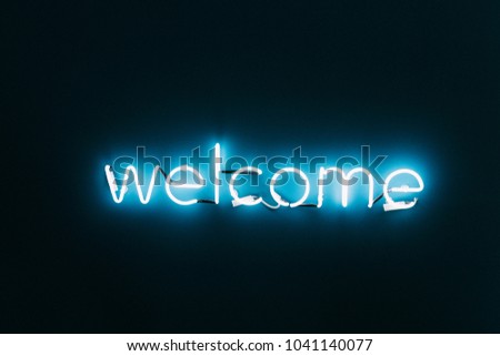 Welcome neon sign on brick wall background